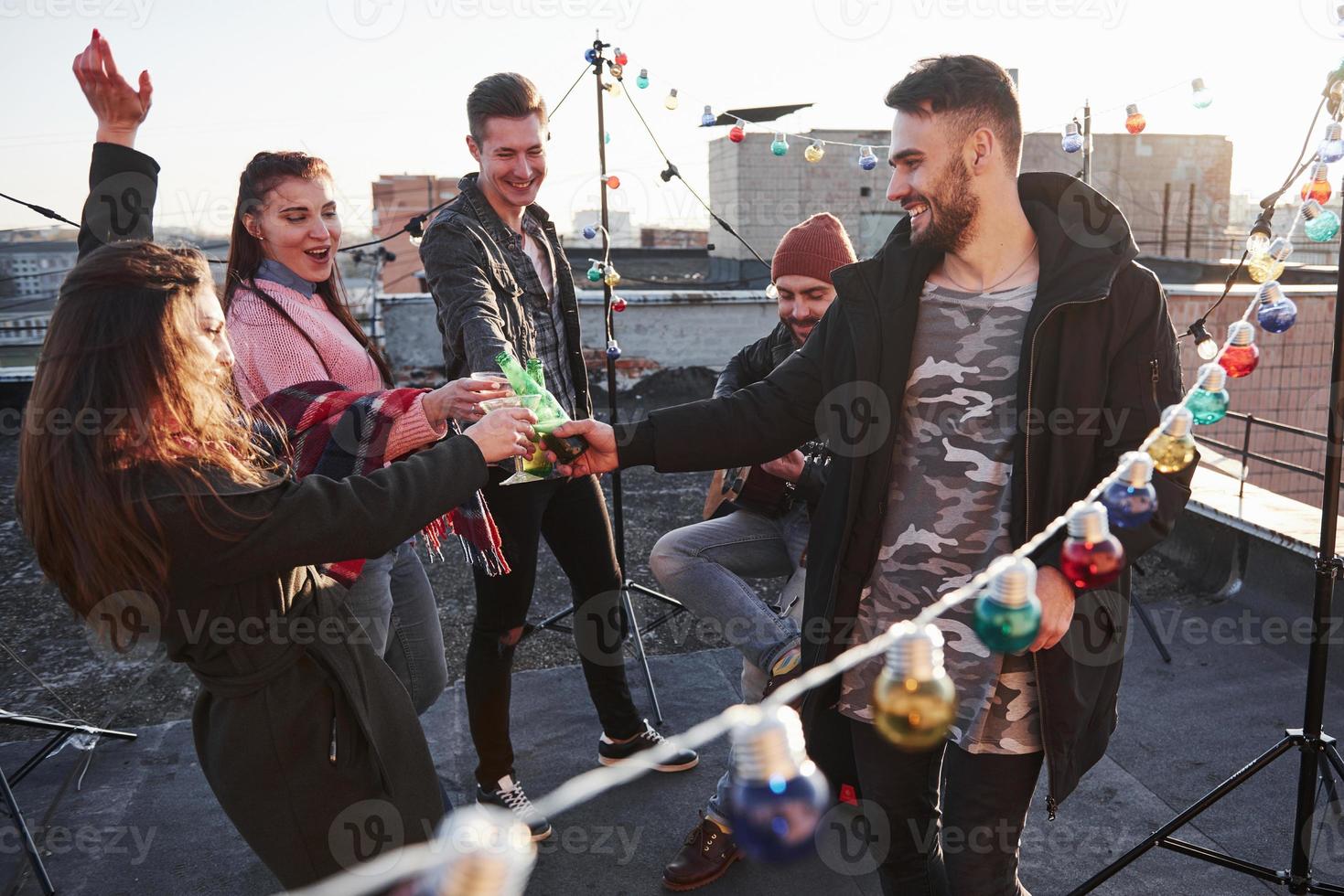 bicchieri bussare tradizionali. lampadine tutt'intorno al posto sul tetto dove si trova un giovane gruppo di amici che hanno deciso di trascorrere il fine settimana con la chitarra e l'alcol? foto