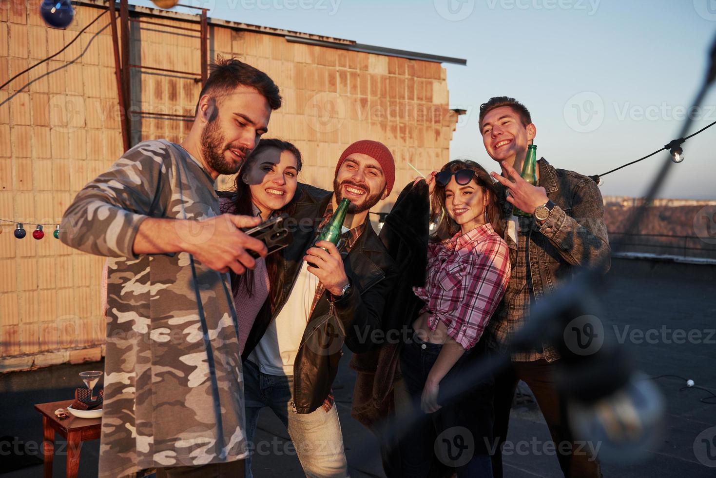 diamo un'occhiata all'immagine. il tempo dei selfie per un gruppo di amici positivi si trova sul tetto con il muro dietro foto
