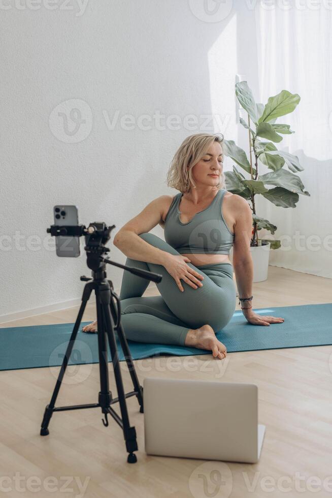 un' 50 anni donna fare in linea yoga a casa foto