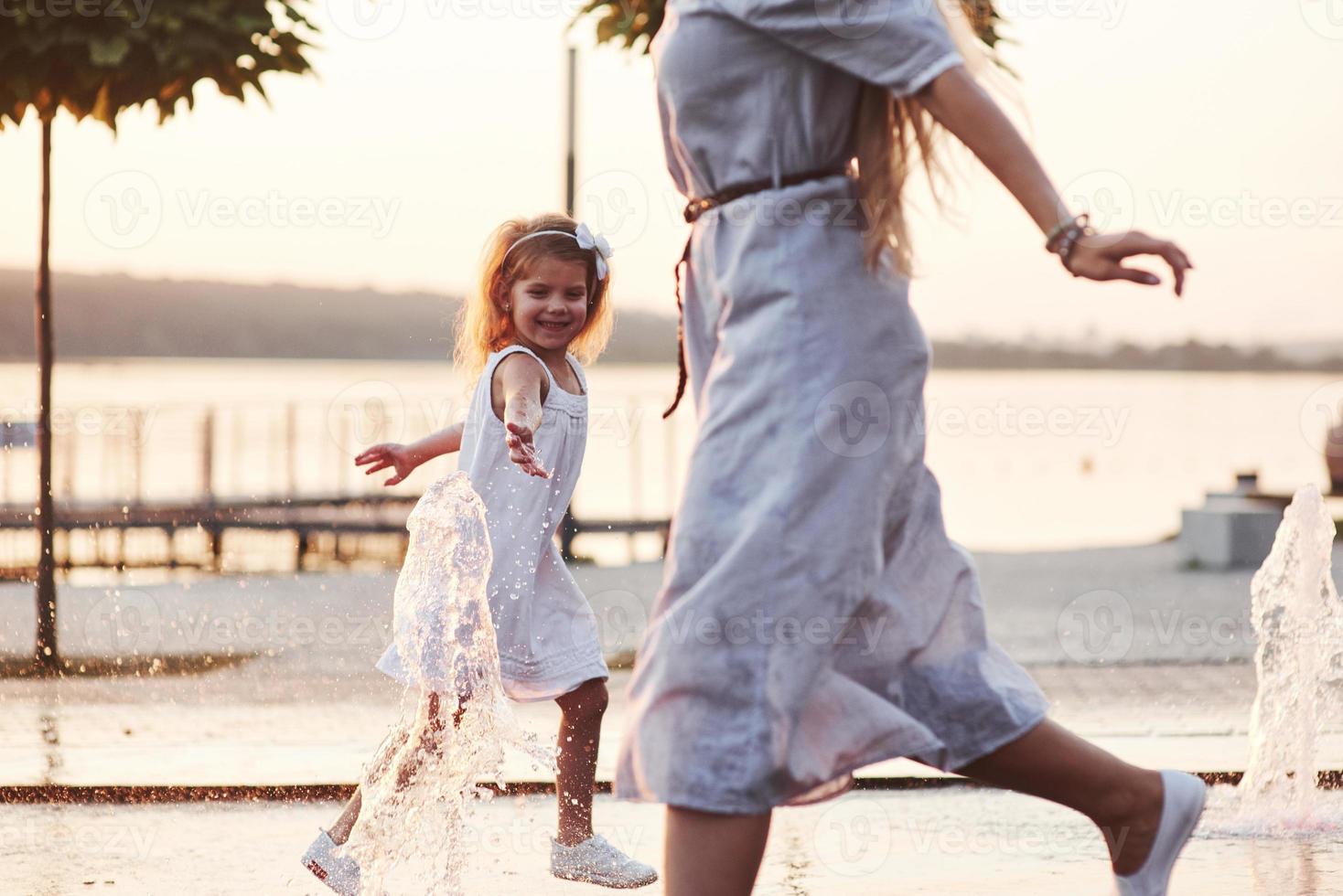 cerca di sfuggire allo scoppio, al gioco. in una calda giornata di sole mamma e figlia decidono di usare la fontana per rinfrescarsi e divertirsi con essa foto