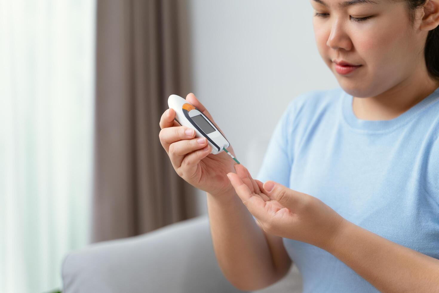 asiatico donna utilizzando lancetta su dito per controllo sangue zucchero livello di glucosio metro, diabete. foto