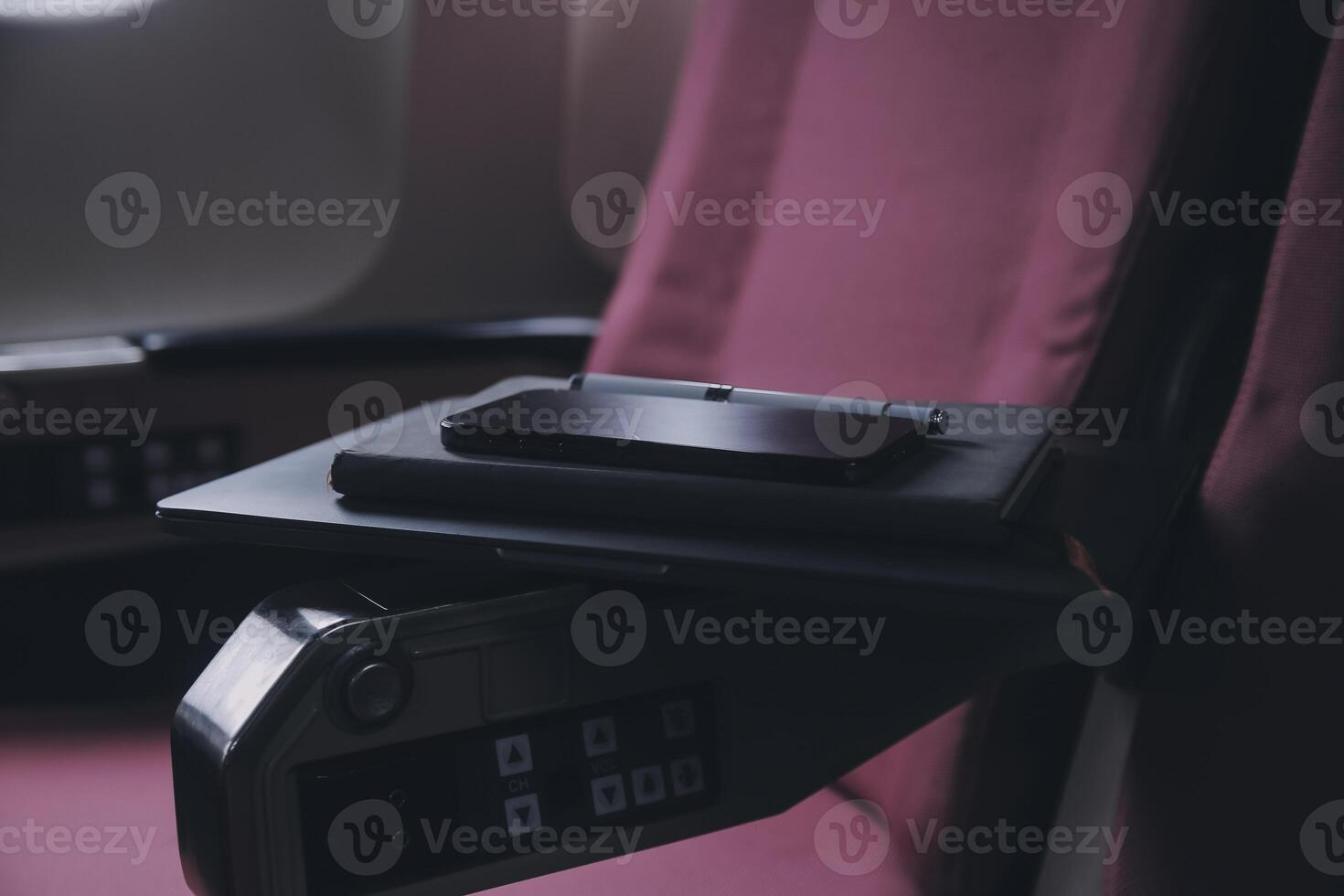 attraente asiatico femmina passeggeri di aereo seduta nel confortevole posto a sedere ascoltando musica nel auricolari mentre Lavorando a moderno il computer portatile computer con finto su la zona utilizzando senza fili connessione su tavola. foto