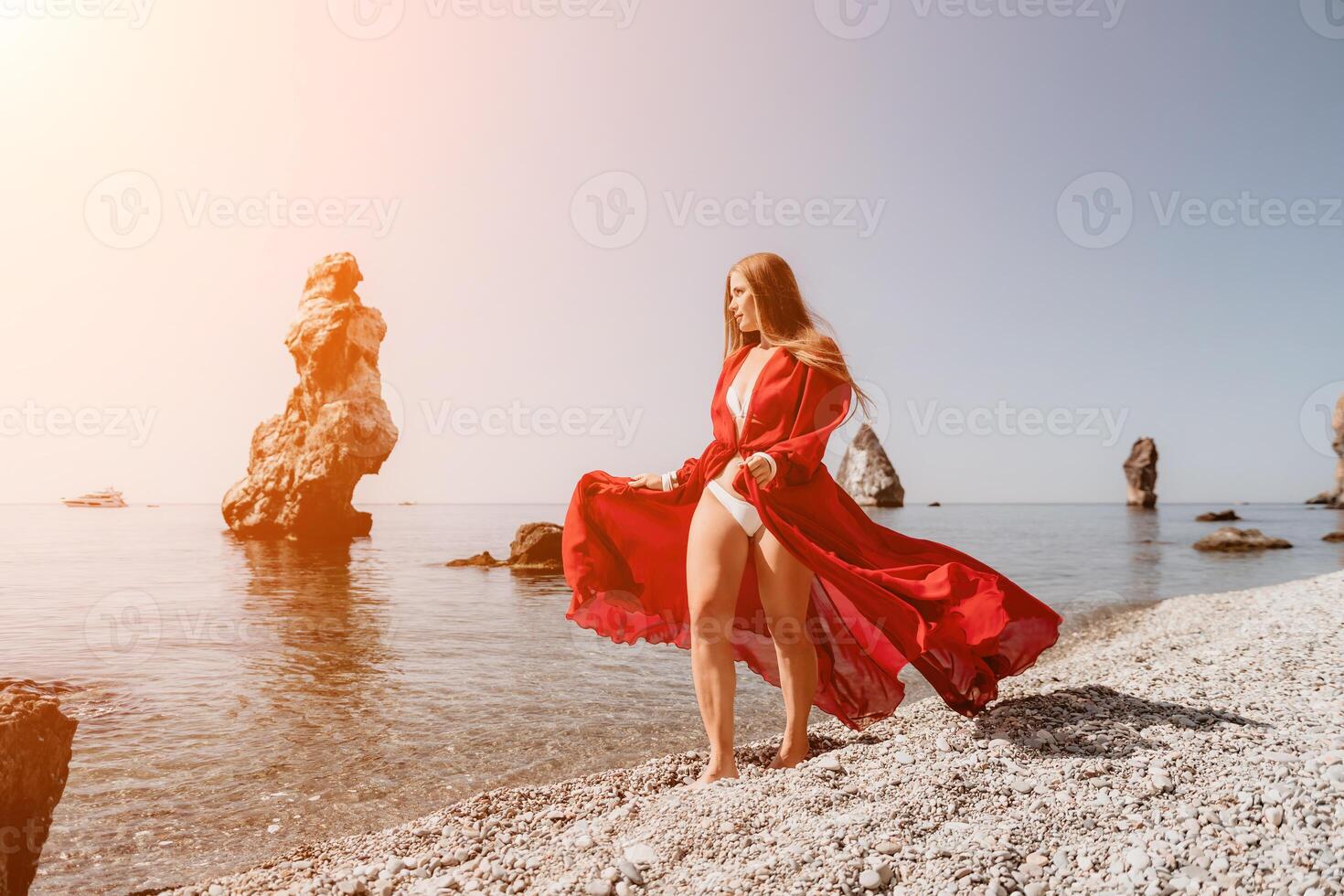 donna viaggio mare. contento turista nel rosso vestito godere assunzione immagine all'aperto per ricordi. donna viaggiatore in posa su il roccia a mare baia circondato di vulcanico montagne, condivisione viaggio avventura viaggio foto