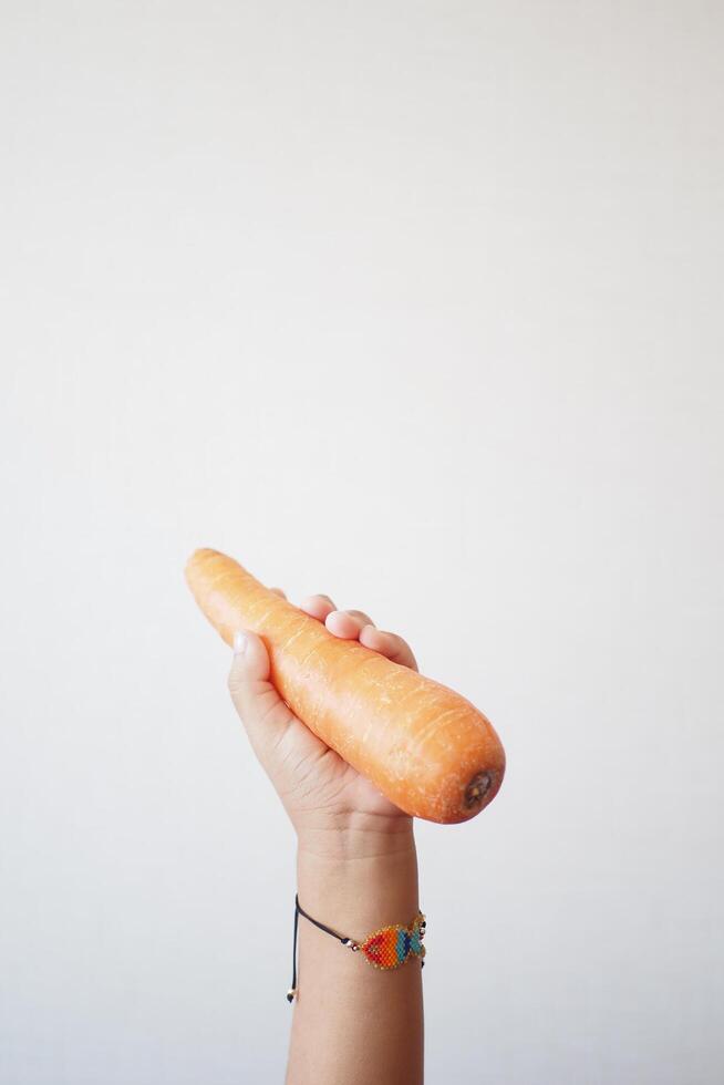 un' bambino è Tenere un' carota come un' cibo ingrediente nel loro mano foto