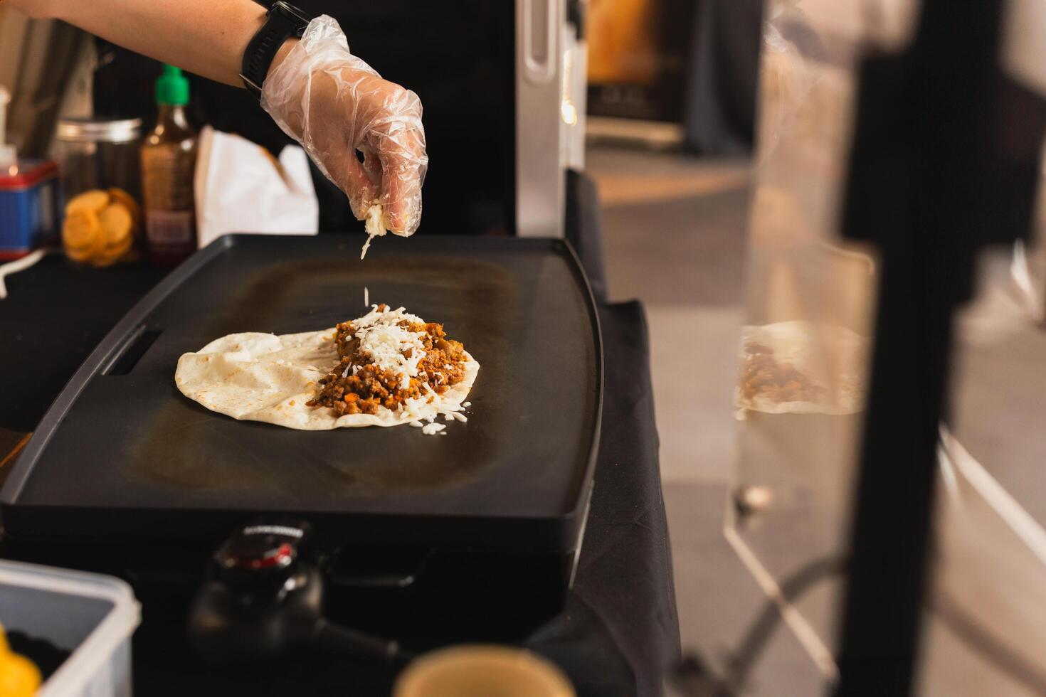 capocuoco spruzzatori un' tortilla con formaggio preparazione fresco Quesadilla su nero griglia. foto