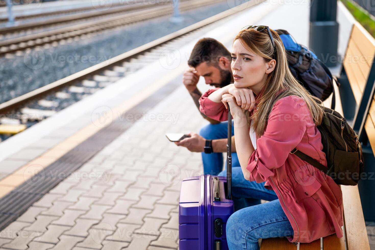 ansioso e stanco coppia seduta a ferrovia stazione e in attesa per arrivo di loro treno. foto