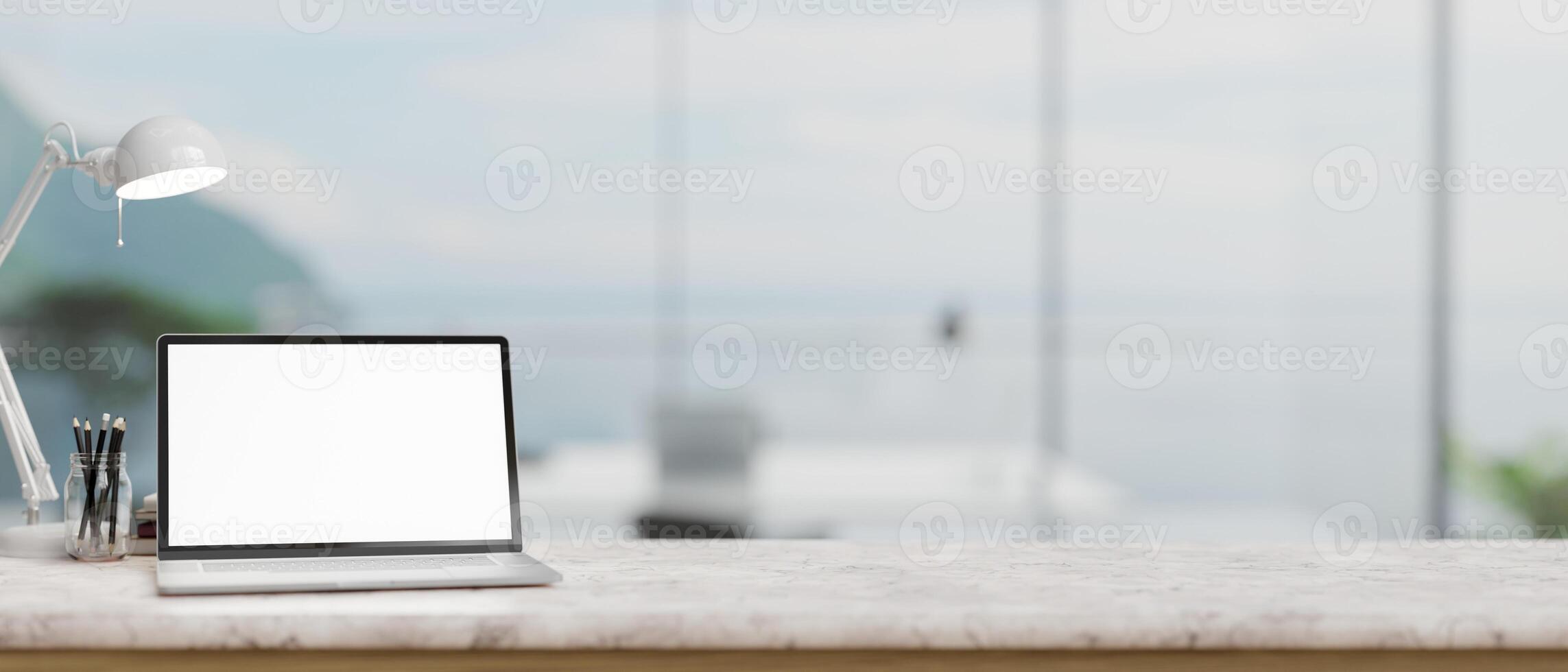 un' il computer portatile modello, un' tavolo lampada, e Stazionario su un' bianca marmo tavolo nel un' moderno spazioso ufficio. foto