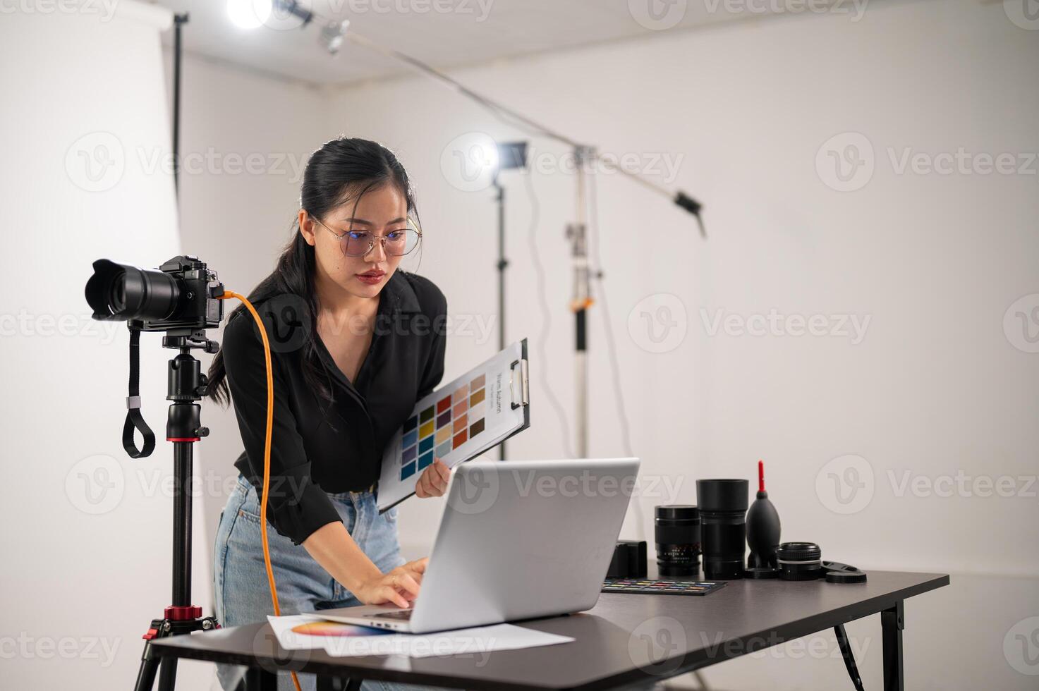 un' freddo, attraente asiatico femmina fotografo produttore è Lavorando nel un' tiro studio. foto