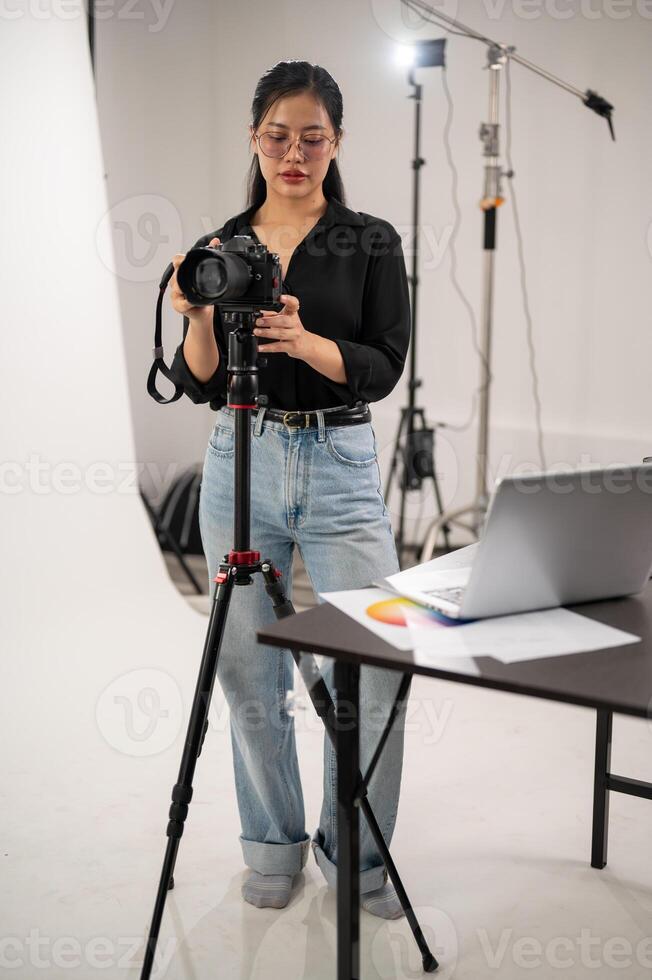 un' professionale asiatico femmina fotografo è regolazione sua dslr telecamera su un' tripode In piedi. foto