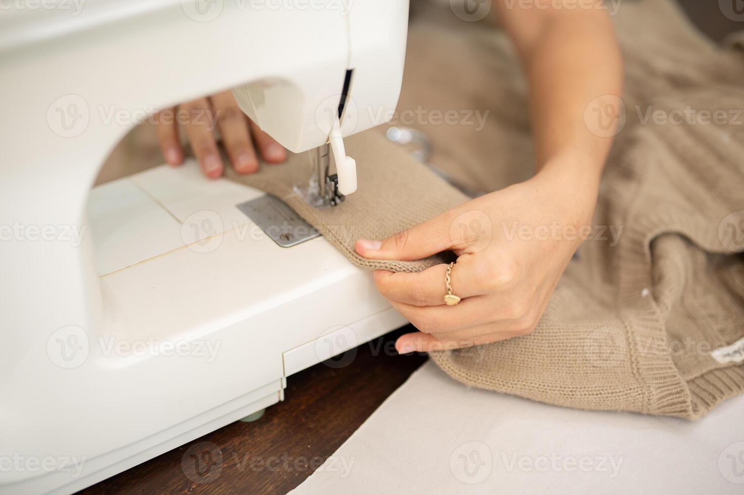 un' avvicinamento Immagine di un' femmina sarto è cucire un' vestito con un' cucire macchina, Lavorando nel sua studio. foto