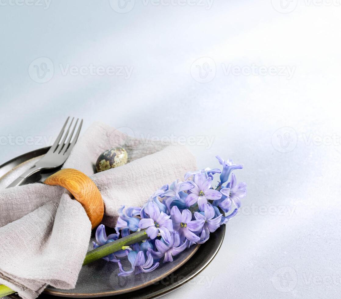 Pasqua tavolo servendo vicino su. grigio piatti, tovagliolo, Quaglia uovo, viola giacinto fiore su leggero grigio. foto