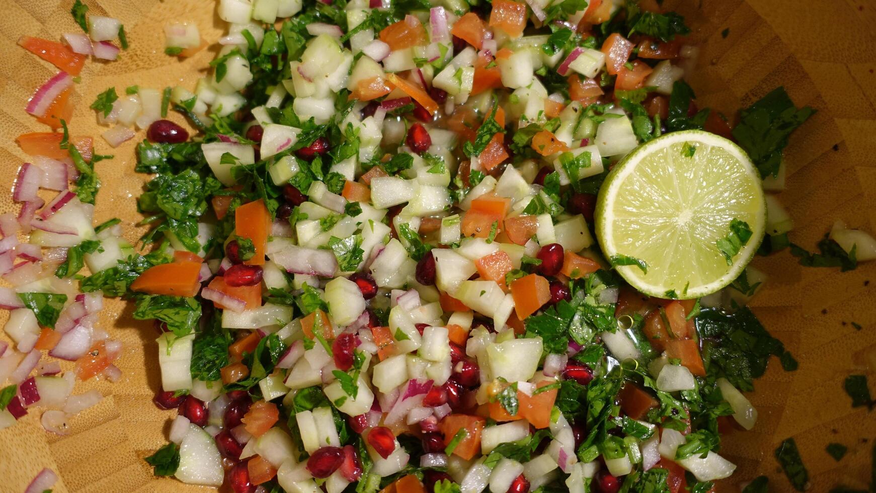 un' insalata con Melograno, rosso cipolla, mela, cetriolo, prezzemolo, pomodori e lime foto