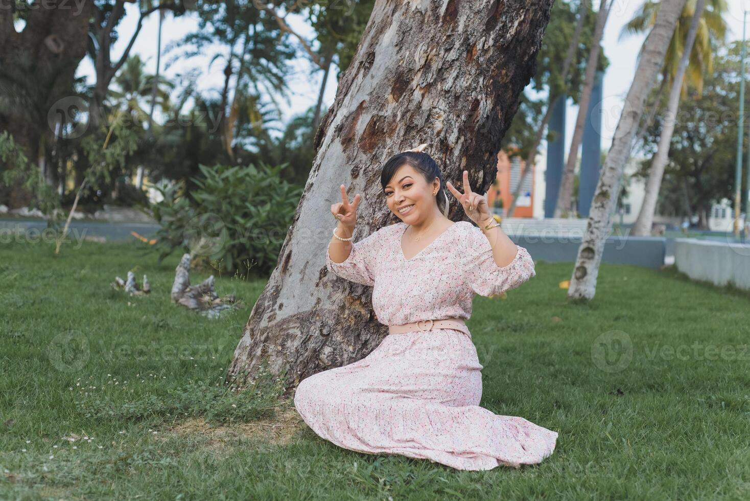 donna con positivo atteggiamento seduto nel il erba nel un' pubblico giardino. foto