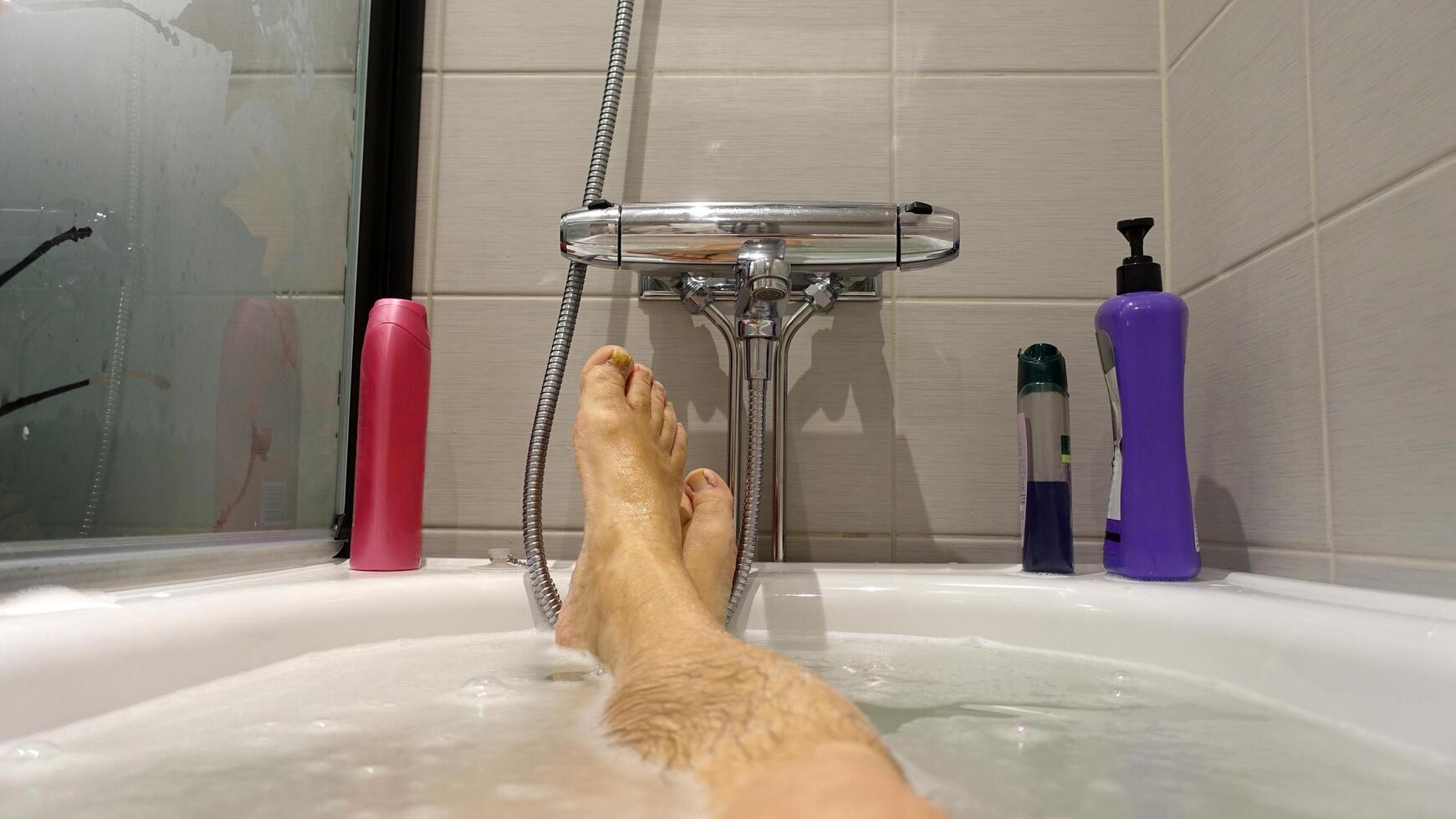 piedi attaccare su di il acqua e sapone schiuma durante un' caldo bagno foto