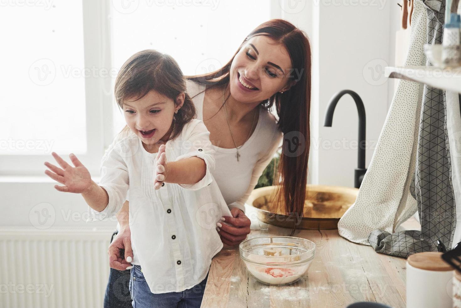 facendo un grande momento. la figlia e la mamma felici stanno preparando insieme prodotti da forno. piccolo aiutante in cucina foto