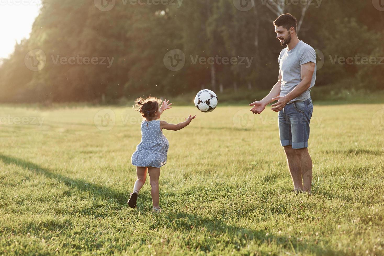 possiamo barare a volte. le mani sono benvenute. papà entusiasta insegna alla figlia come giocare al suo gioco preferito. è il calcio e anche le bambine possono giocarci foto