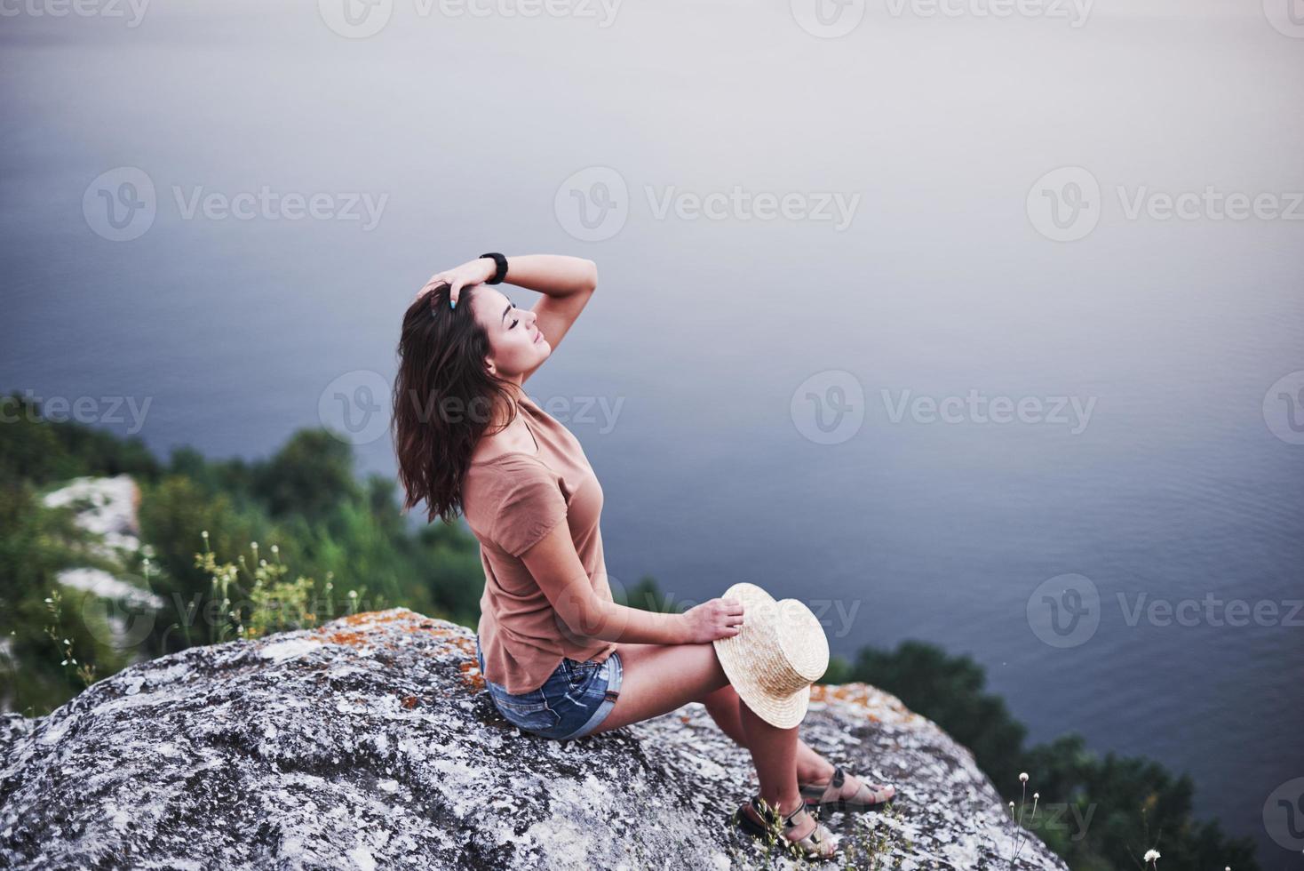 aria fresca. attraente ragazza turistica in posa sul bordo della montagna con lago di acqua limpida in background foto