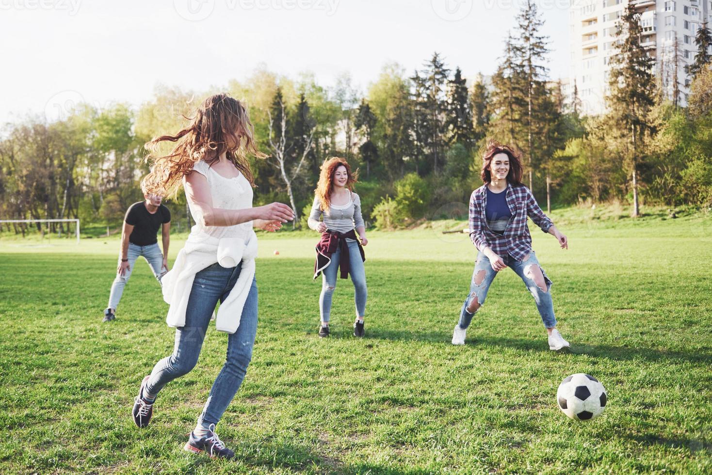 un gruppo di amici in abbigliamento casual gioca a calcio all'aria aperta. le persone si divertono e si divertono. riposo attivo e tramonto panoramico foto