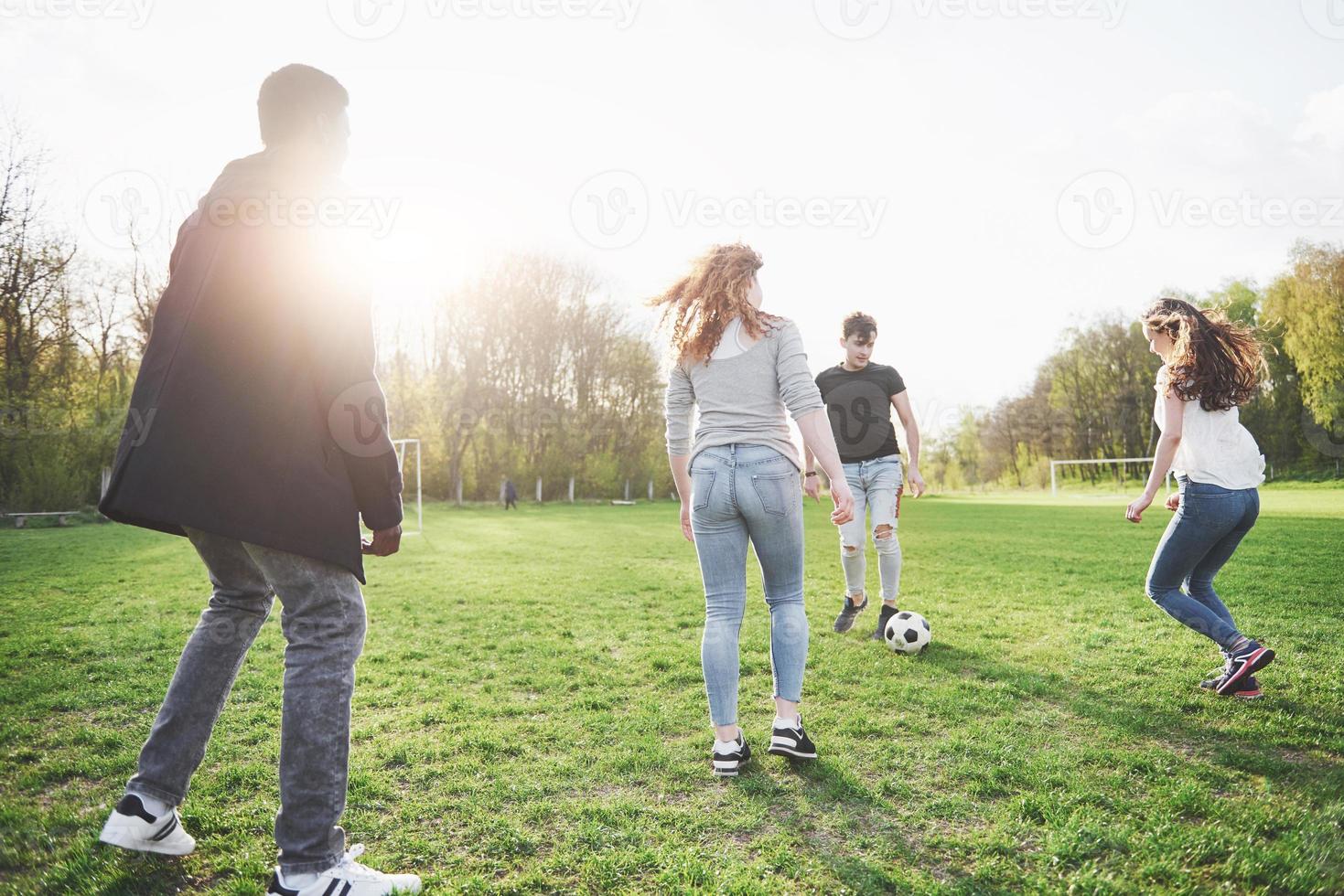 un gruppo di amici in abbigliamento casual gioca a calcio all'aria aperta. le persone si divertono e si divertono. riposo attivo e tramonto panoramico foto