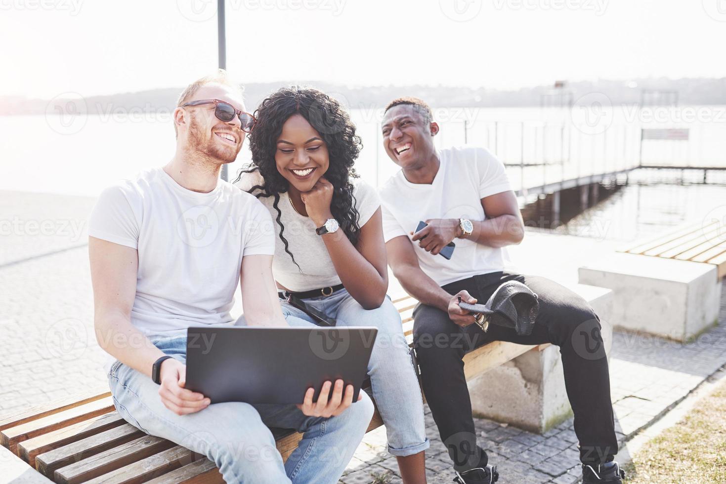 bellissimi amici multietnici che usano un laptop per strada. concetto di stile di vita giovanile foto