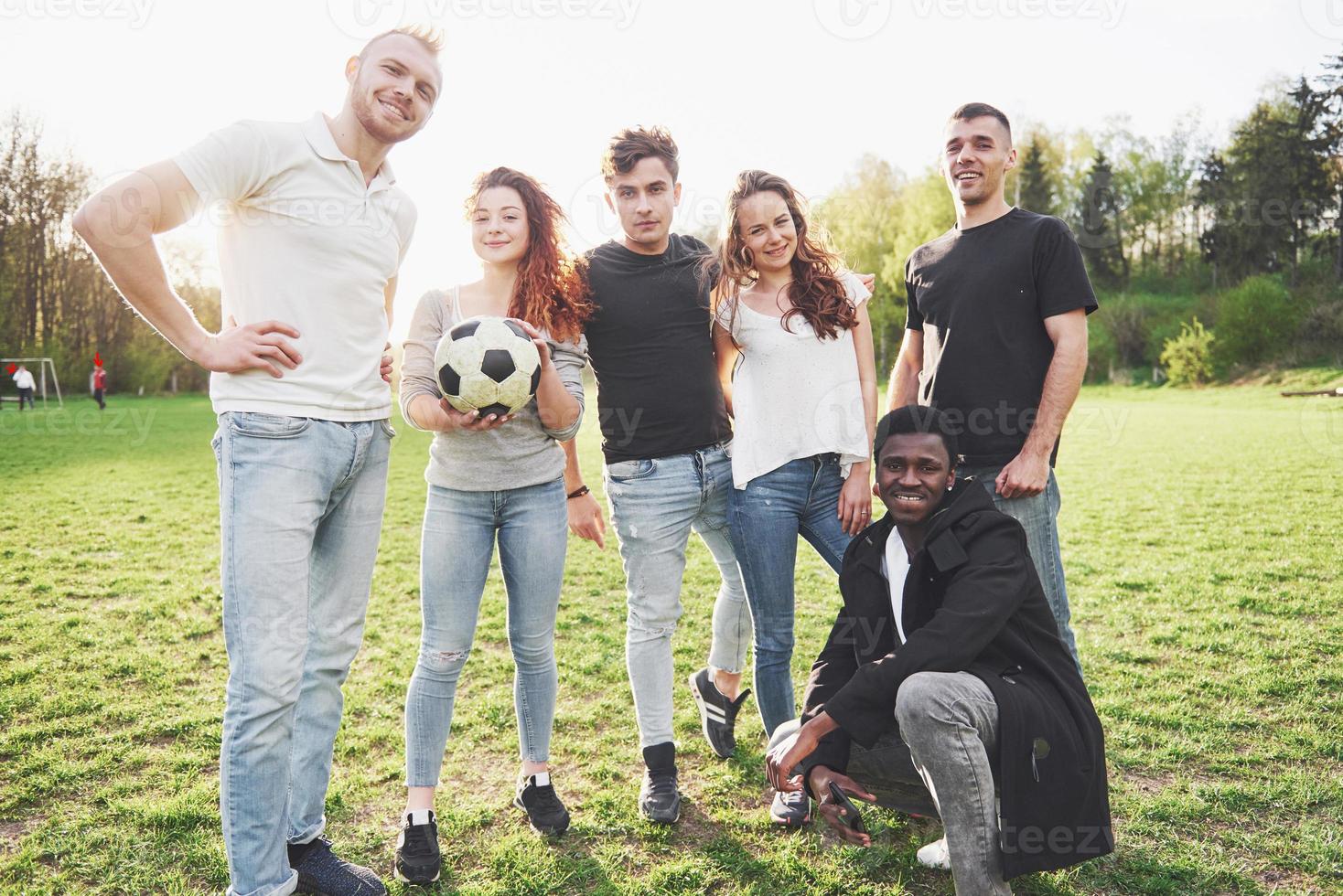 un gruppo di amici in abbigliamento casual fa sephi sul campo di calcio. le persone si divertono e si divertono. riposo attivo e tramonto panoramico foto