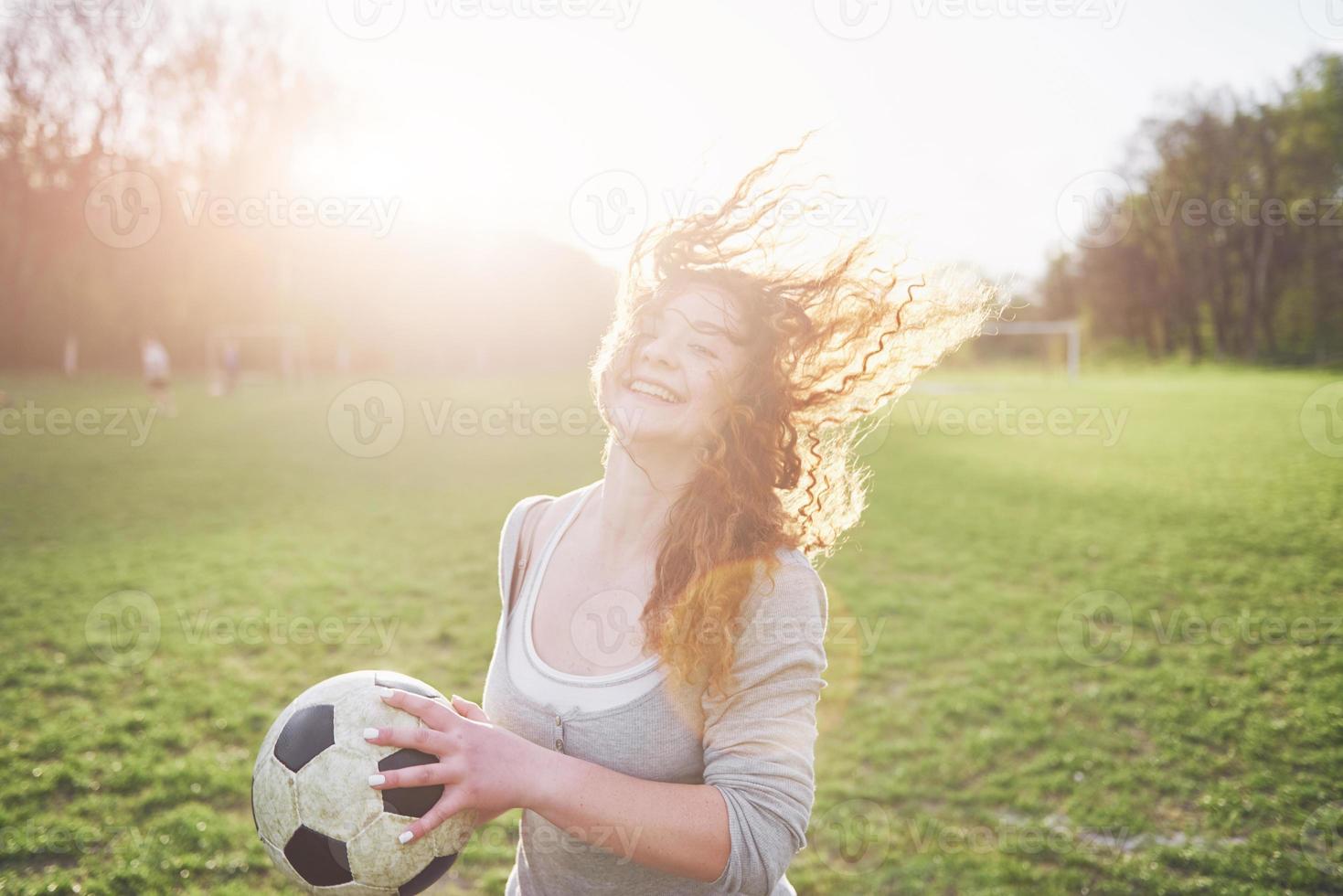 giovane ragazza sexy dai capelli rossi in giocatore occasionale nello stadio di calcio al tramonto foto