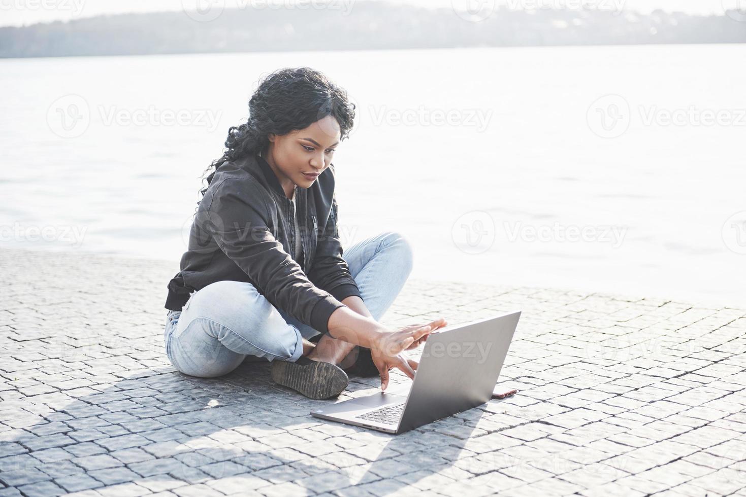 giovane donna per strada che lavora al laptop foto