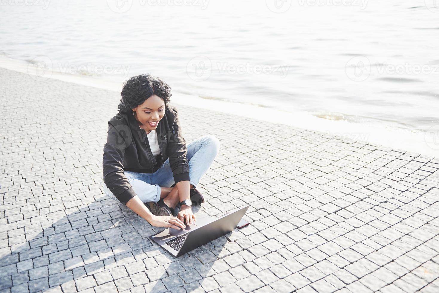 giovane donna per strada che lavora al laptop foto