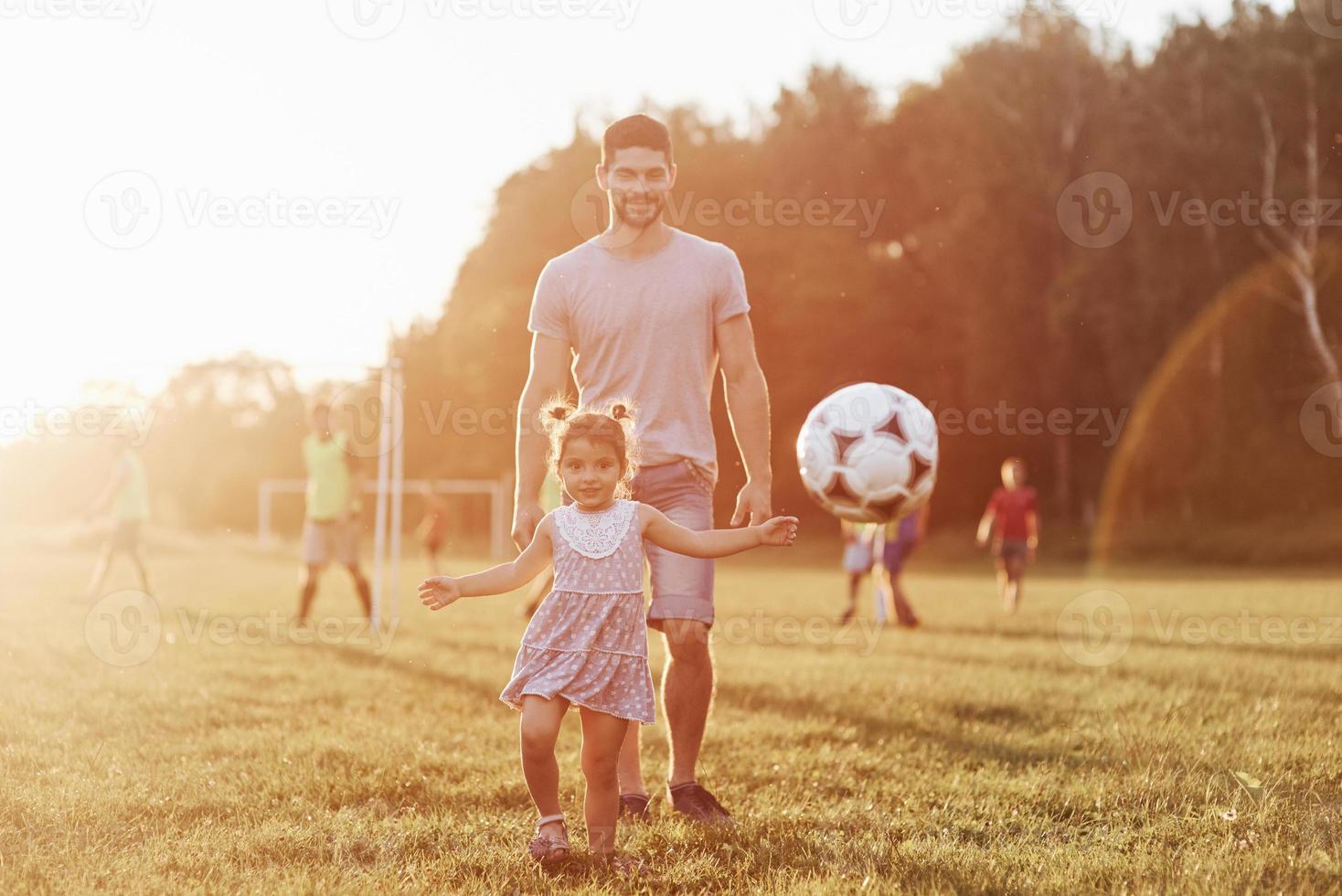 guarda i cameramen, non è un giocatore di calcio. foto di papà con sua figlia in un bellissimo prato e boschi sullo sfondo