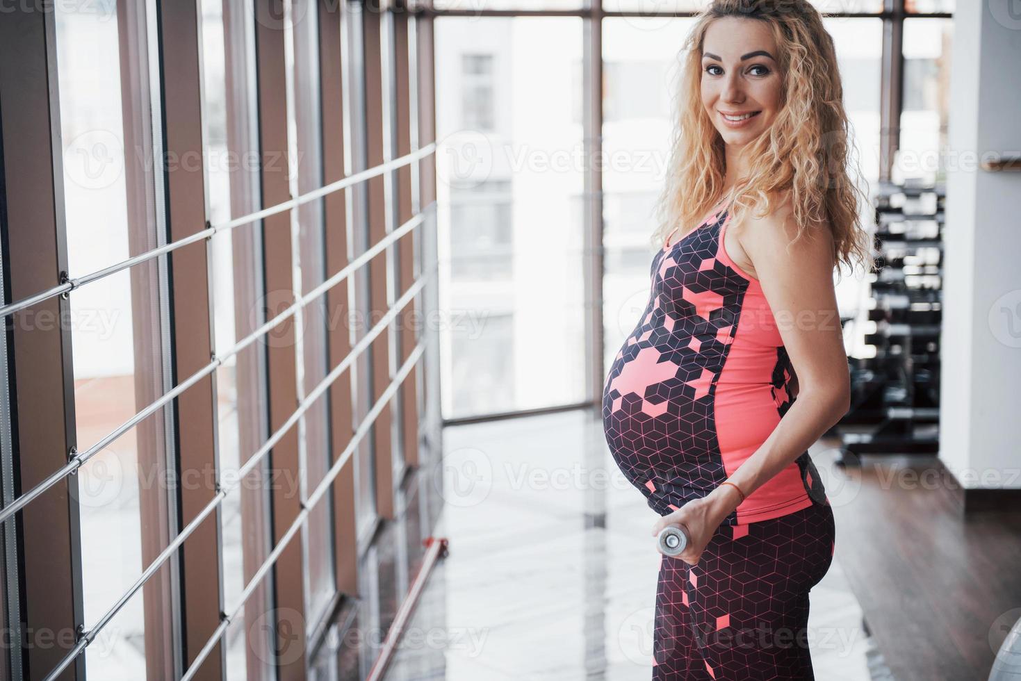 il concetto di una donna incinta fa sport e fitness e conduce uno stile di vita sano in palestra foto