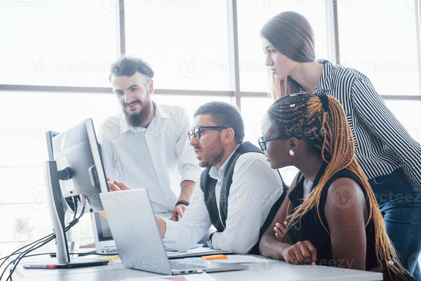 giovani dipendenti seduti in ufficio al tavolo e utilizzando un laptop, un concetto di incontro di brainstorming di lavoro di squadra. foto