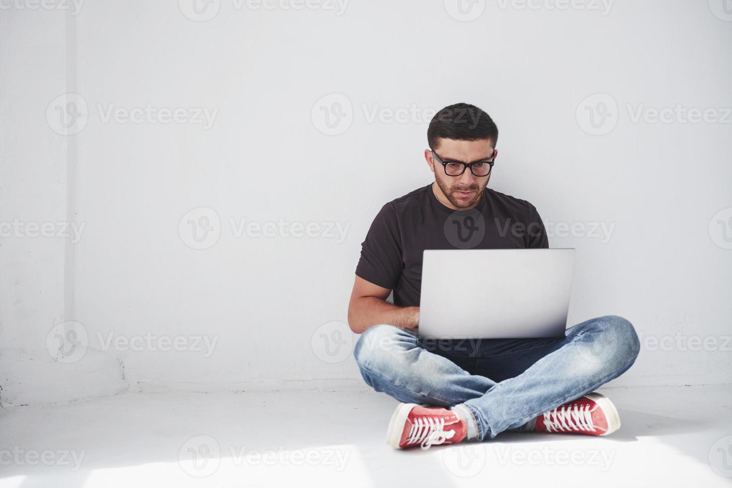 bel giovane con laptop e controlla il suo orario su sfondo bianco foto