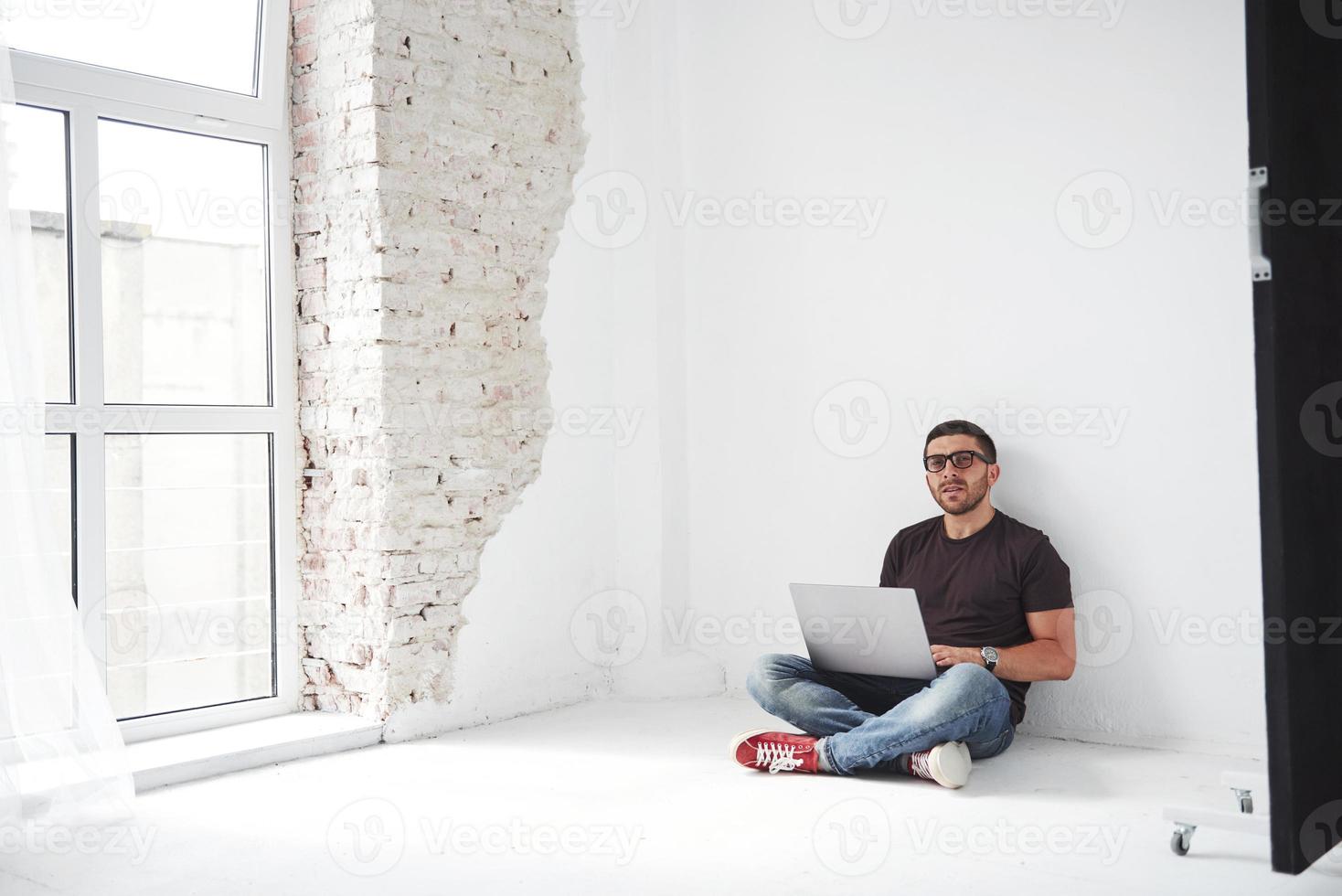 bel giovane con laptop e controlla il suo orario su sfondo bianco foto