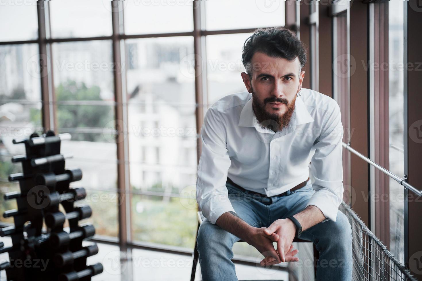 un uomo seducente in una camicia bianca che guarda la telecamera. foto