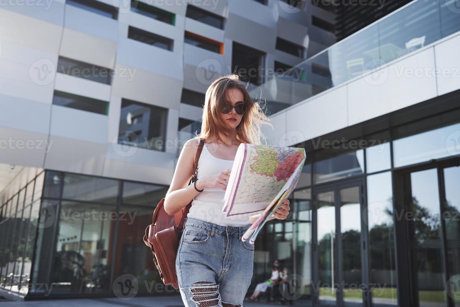 turista femminile con mappa che visita una nuova città e sta cercando un modo per raggiungere l'hotel foto