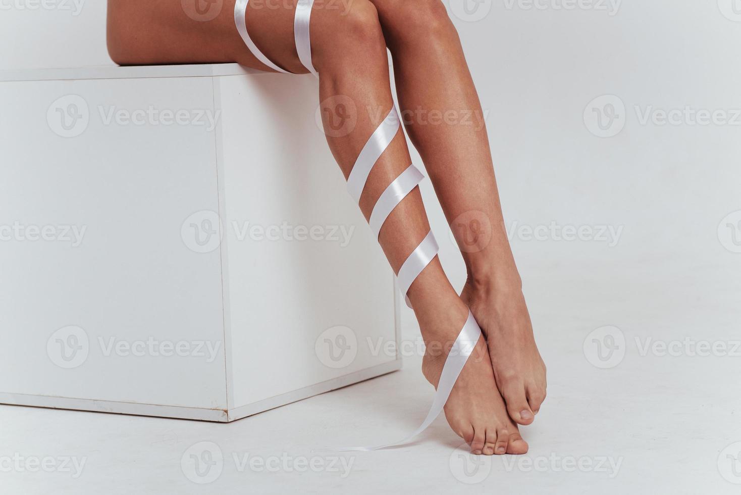 gambe femminili all'interno bianco con nastri sopra. foto ritagliata