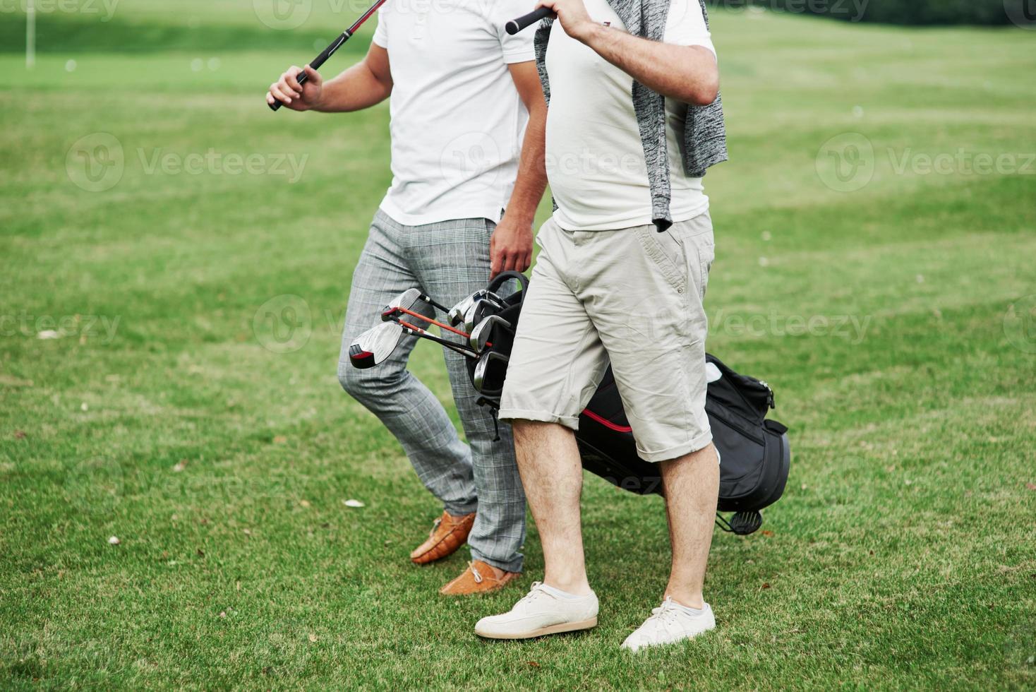 foto ritagliata di due amici sul campo sportivo con attrezzatura da golf