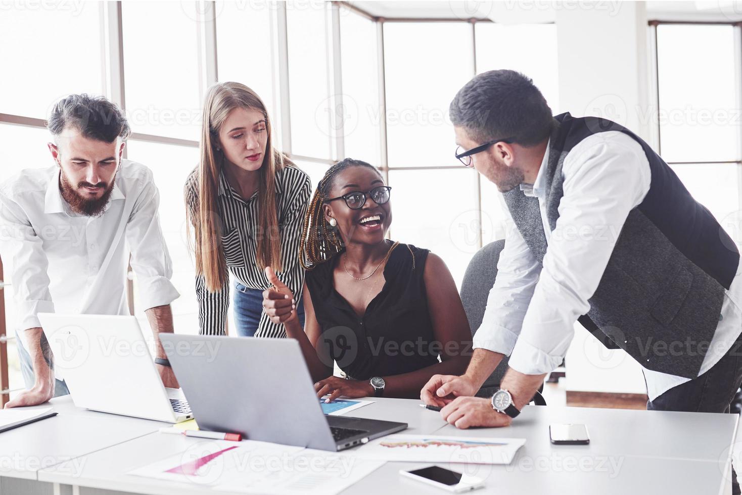 sarà facile. quattro dipendenti multirazziali lavorano in ufficio usando il laptop sul tavolo foto