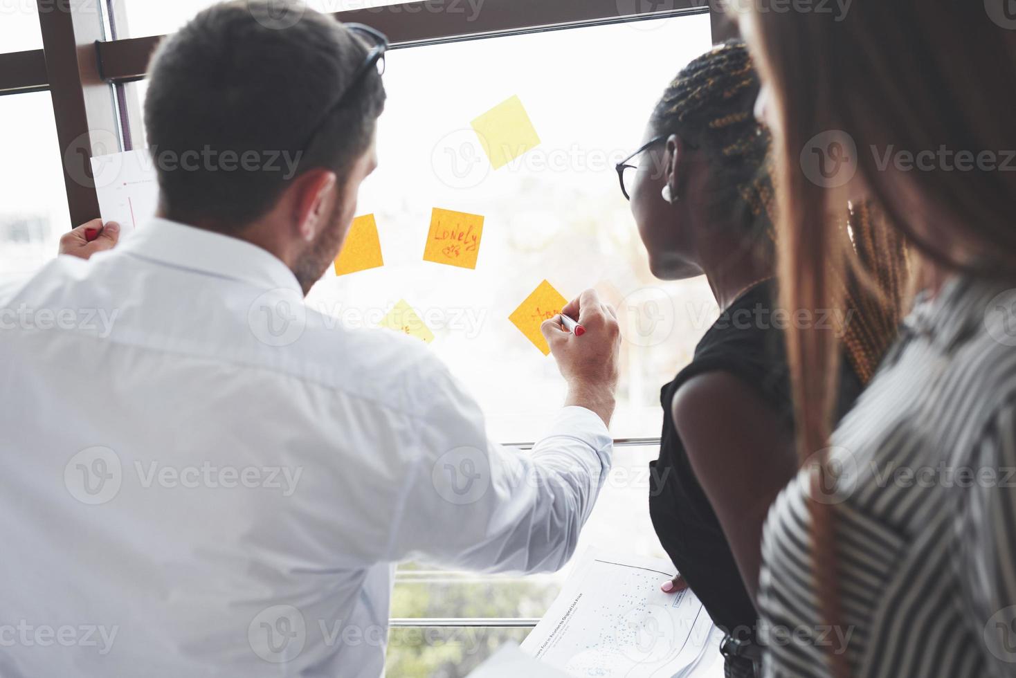 scrivendo su alcuni adesivi. le persone in ufficio hanno un lavoro creativo foto