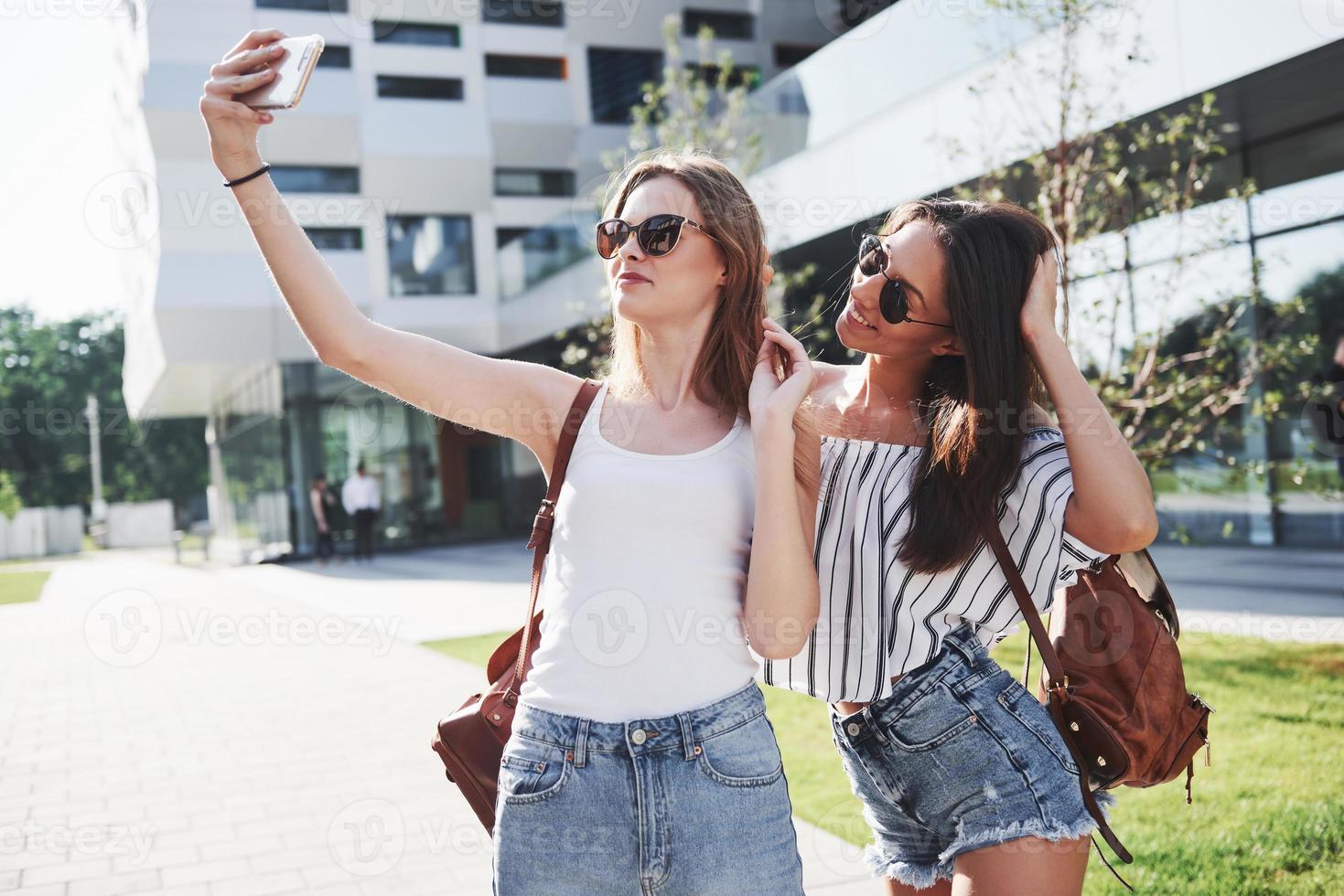 due belle giovani studentesse felici con lo zaino vicino al campus dell'università e fare selfie foto. concetto di educazione e tempo libero foto