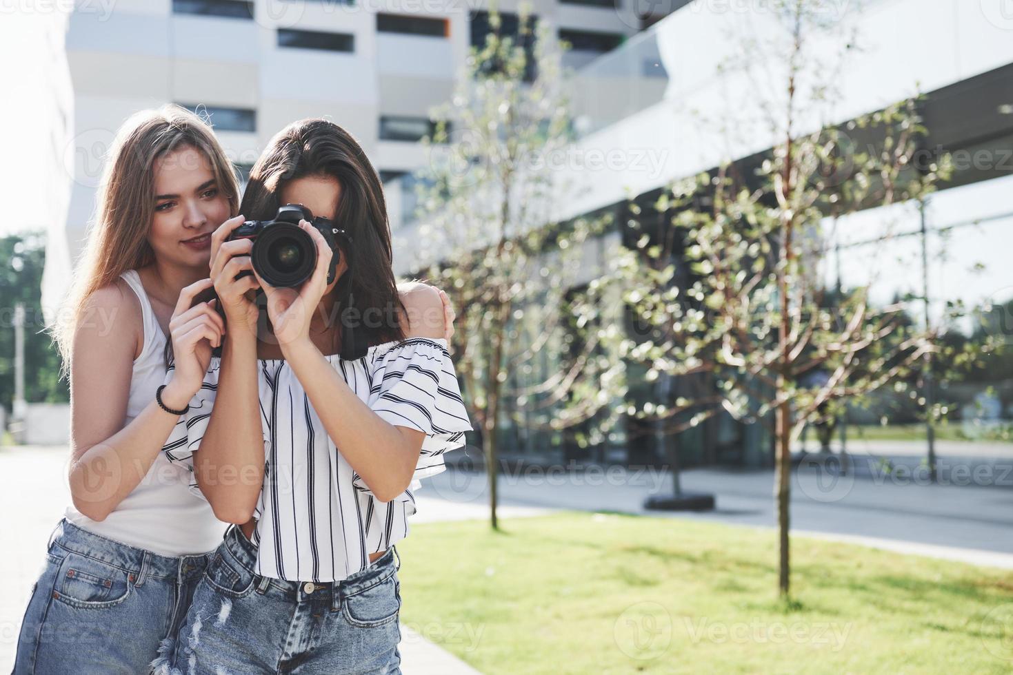 due belle amiche della ragazza con la macchina fotografica scattano foto insieme e passeggiano per la città