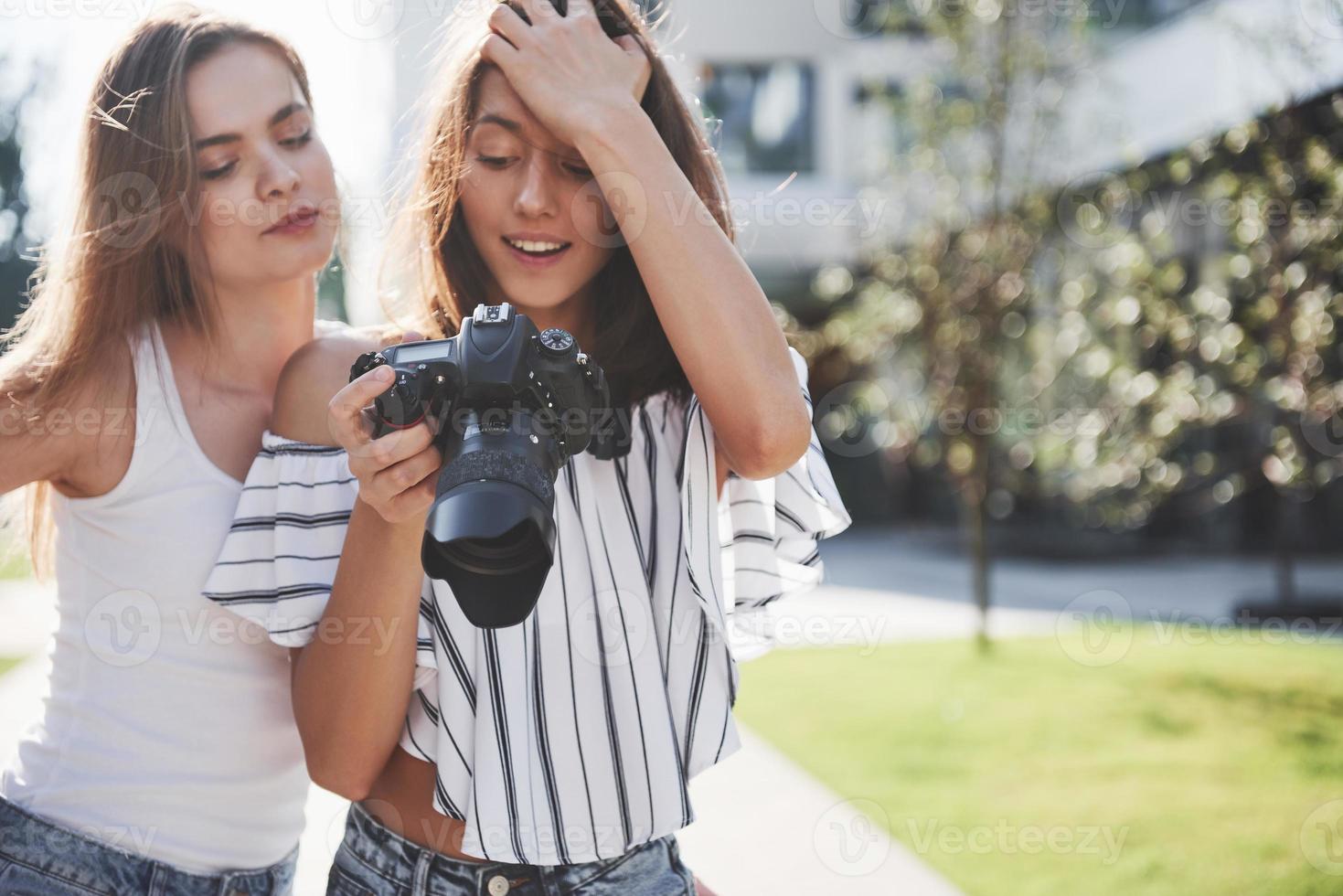 due belle amiche della ragazza con la macchina fotografica scattano foto insieme e passeggiano per la città