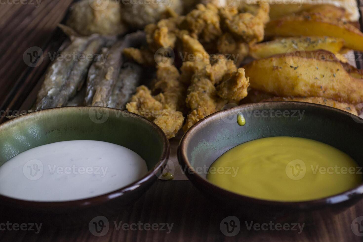 fritte patate con pesce, formaggio bastoni e salse. foto