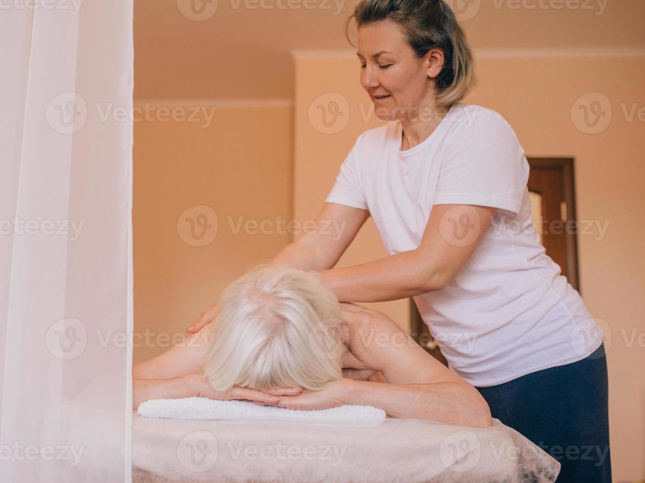 donna elegante caucasica anziana con i capelli grigi posa su un massaggio. anti età, stile di vita sano, concetto di massaggio foto