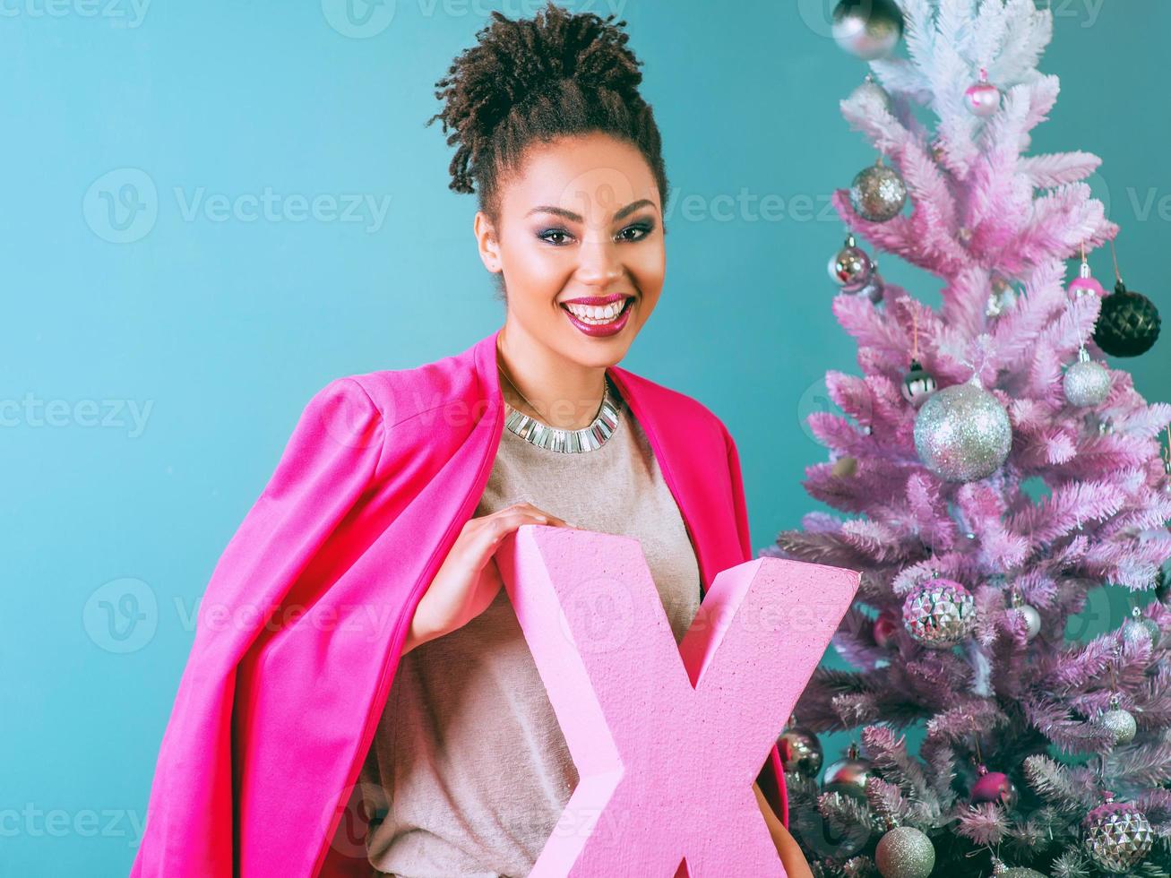 triste donna afroamericana vicino all'albero di natale delusa dal regalo di natale. natale, capodanno, frustrazione, felicità, concetto di vacanze foto