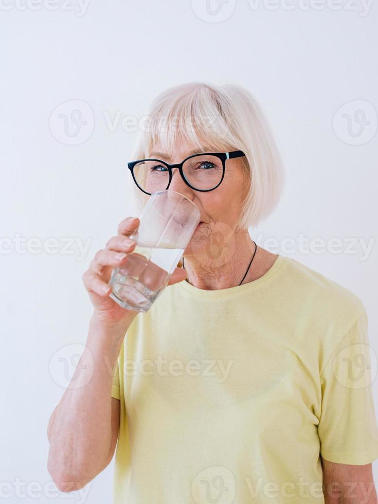 donna anziana che tiene bicchiere d'acqua e acqua potabile. stile di vita sano, sport, concetto anti età foto