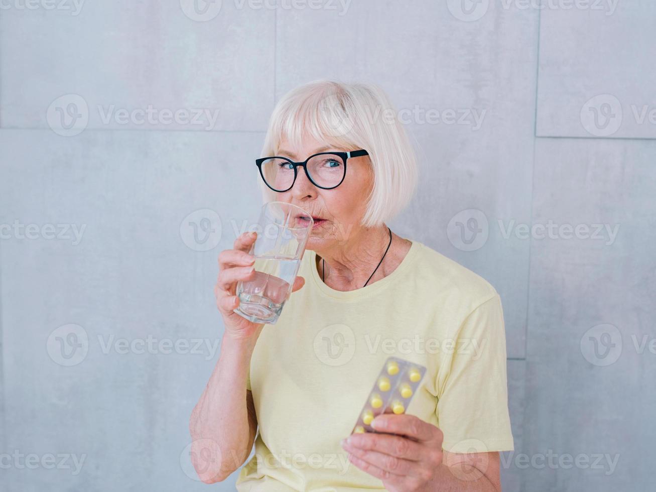 donna anziana che tiene bicchiere d'acqua e acqua potabile. stile di vita sano, sport, concetto anti età foto