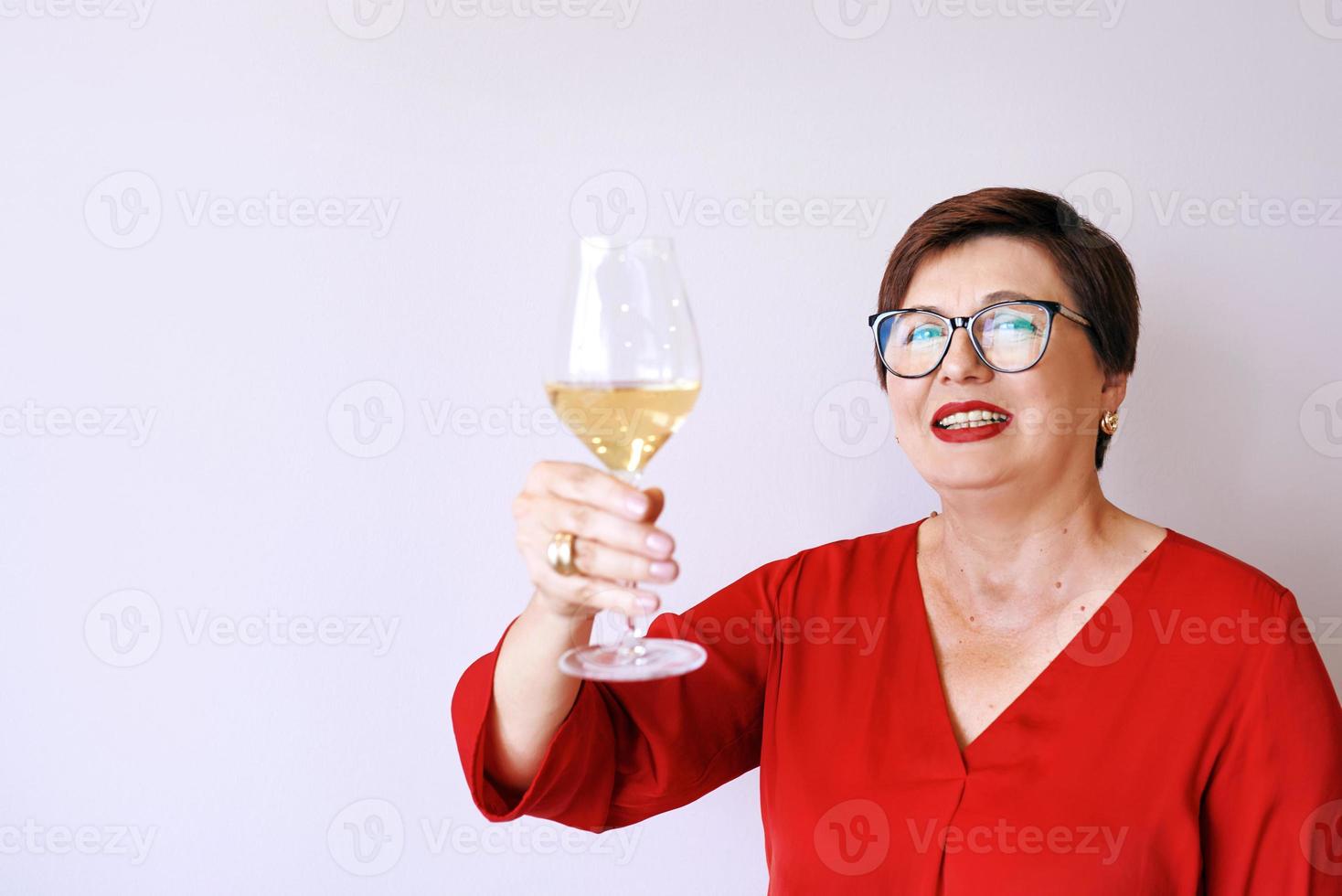 elegante donna anziana matura con un bicchiere di vino. divertimento, festa, stile, stile di vita, lavoro, alcol, concetto di celebrazione foto