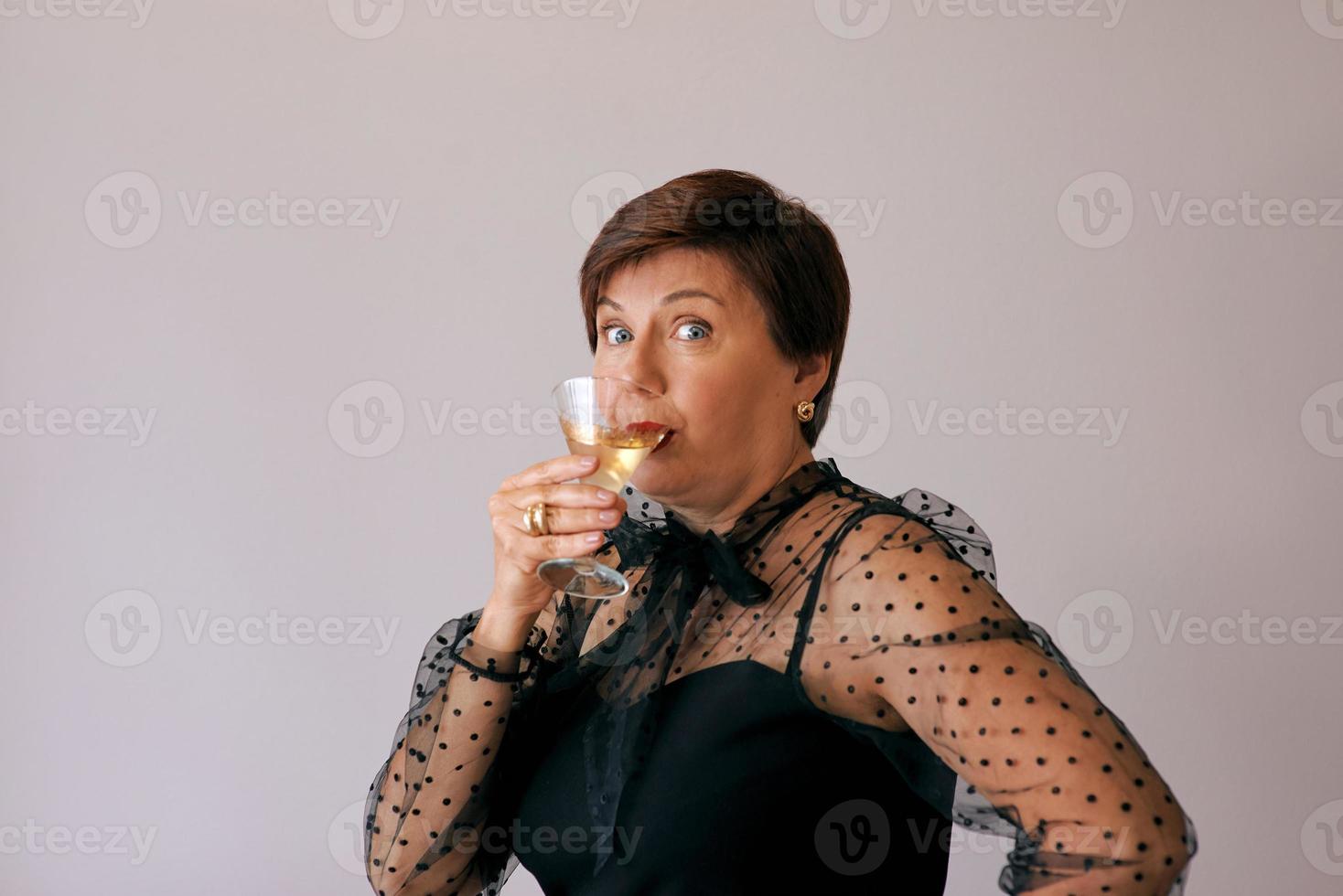 elegante donna anziana matura con un bicchiere di vino. divertimento, festa, stile, stile di vita, lavoro, alcol, concetto di celebrazione foto