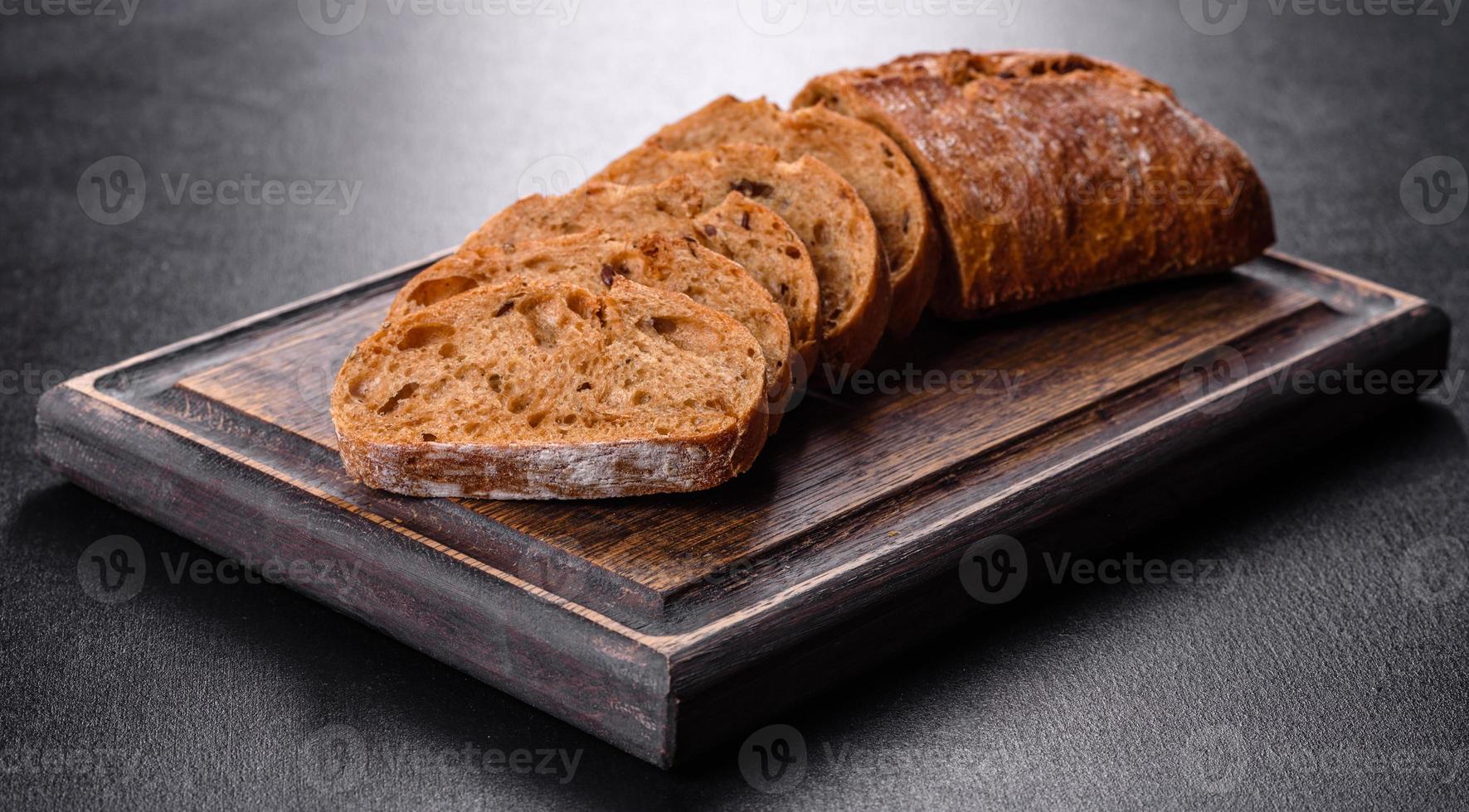 delizioso pane nero fresco affettato con fette su uno sfondo di cemento scuro foto